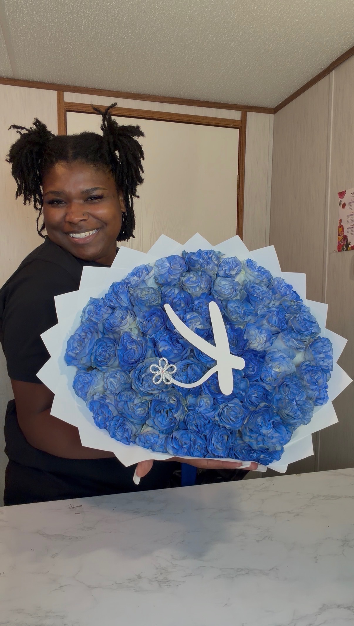 Tyreeka, founder of Crowned In Eden, holding a custom blue rose bouquet
